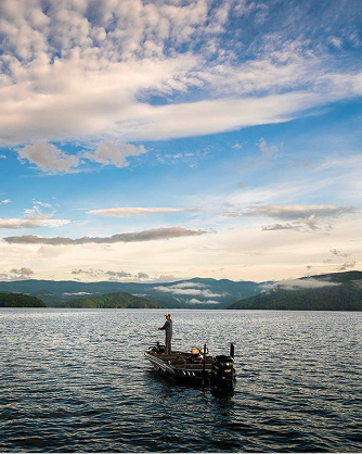 Angler fishing from boat in middle of water using Fenwick Rod